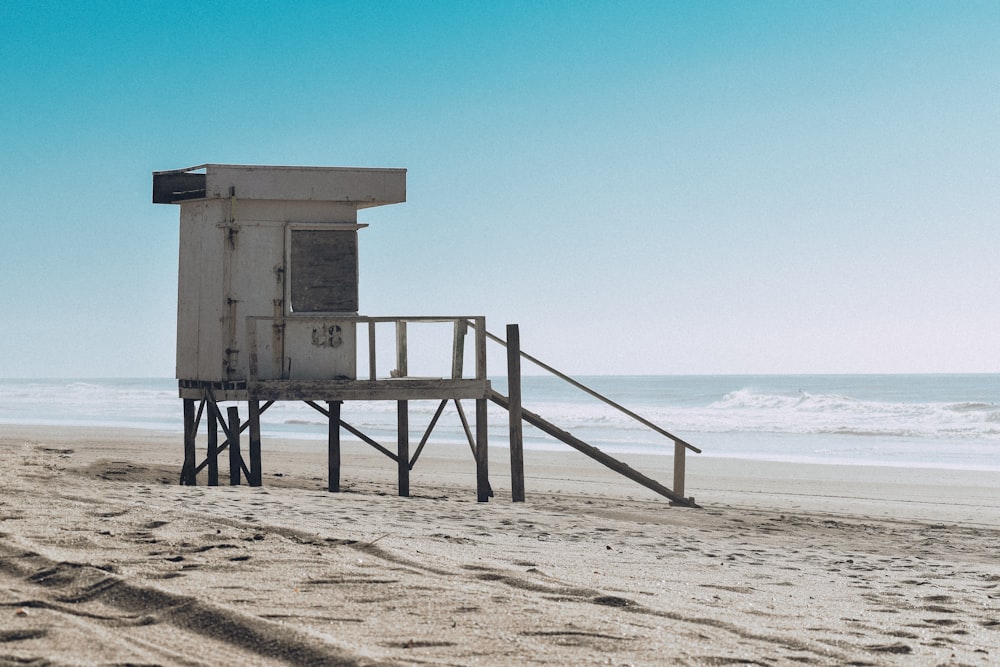 white wooden lifeguard house on beach shore during daytime