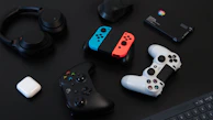 Mobile accessories including neon-lit gaming earbuds and a futuristic phone case arranged on a black surface.