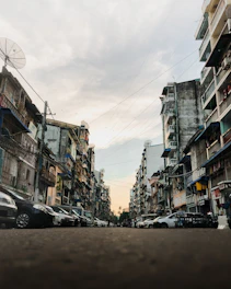 cars parked on side of the road in between buildings during daytime