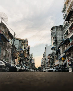 cars parked on side of the road in between buildings during daytime
