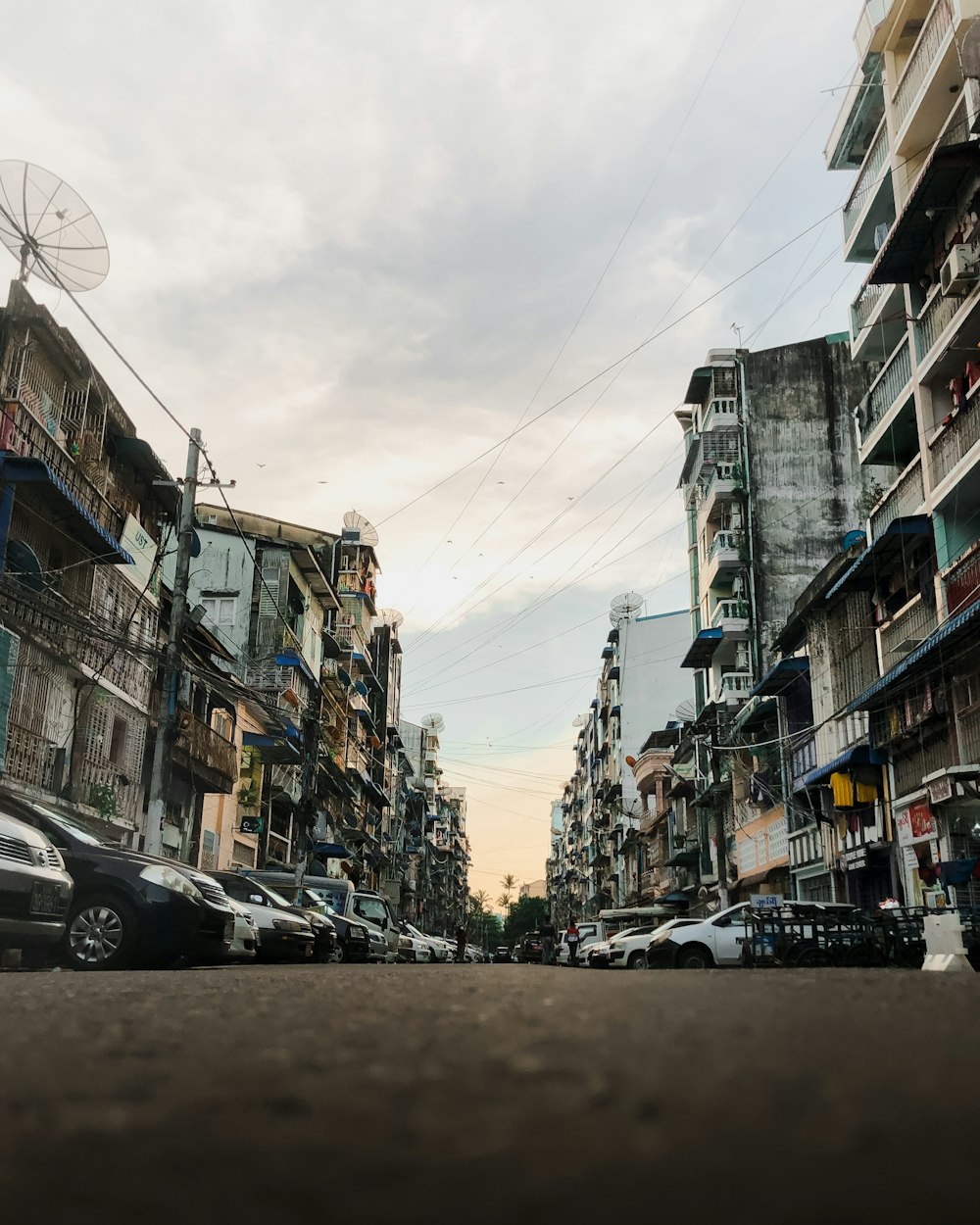 cars parked on side of the road in between buildings during daytime