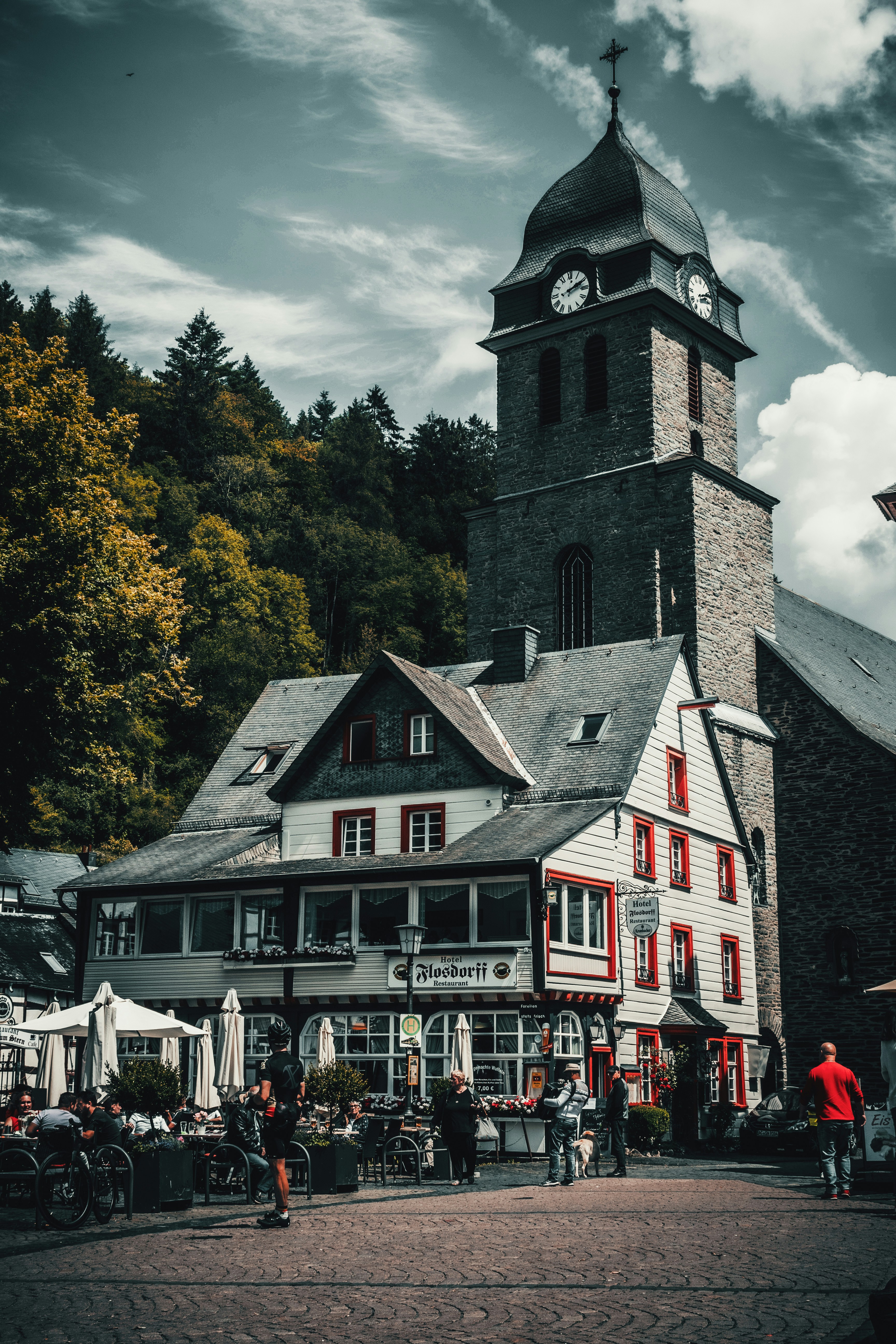 white and brown concrete building near green trees under white clouds during daytime