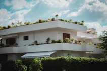 white concrete building near green trees under blue sky during daytime