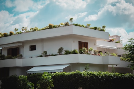white concrete building near green trees under blue sky during daytime