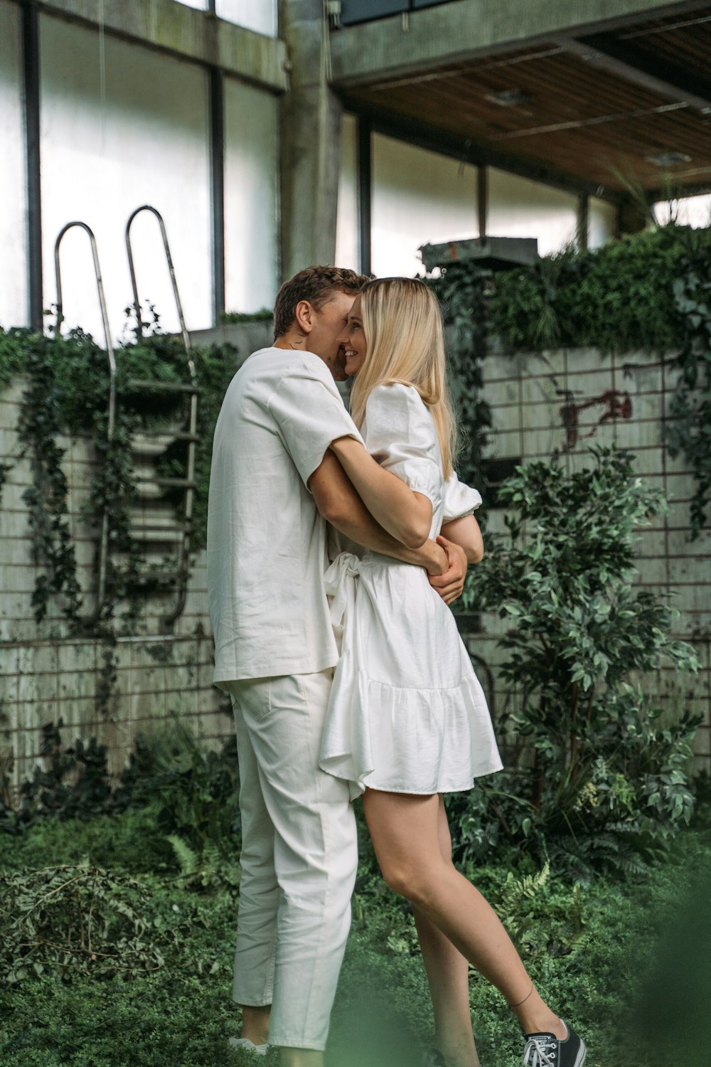 man in white shirt hugging woman in white dress