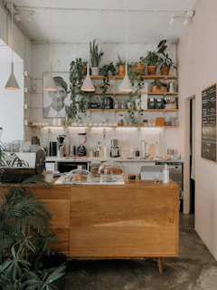 Cozy coffee shop interior with cakes displayed on wooden shelves and a welcoming counter.
