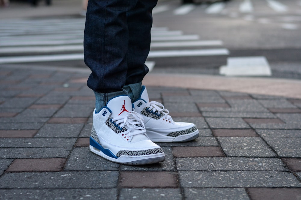 person in blue denim jeans and white and blue nike sneakers