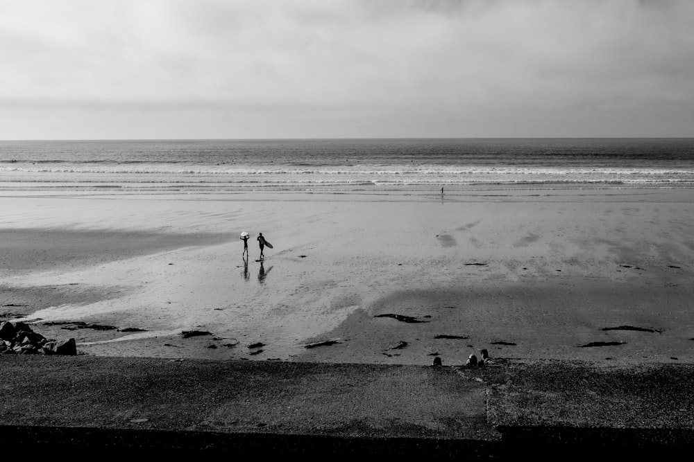 grayscale photo of person walking on beach