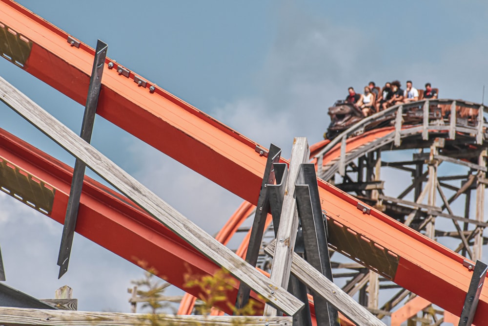 people riding red roller coaster during daytime