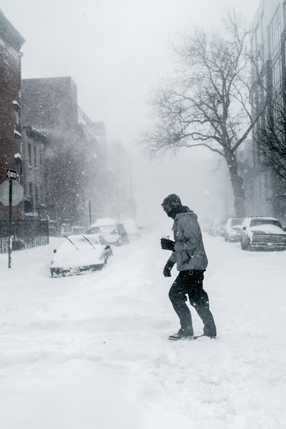 man in gray jacket and black pants walking on snow covered road during daytime