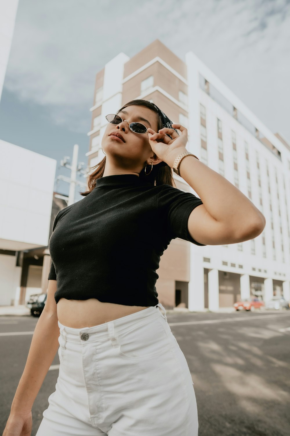 woman in black shirt and white denim shorts wearing black sunglasses