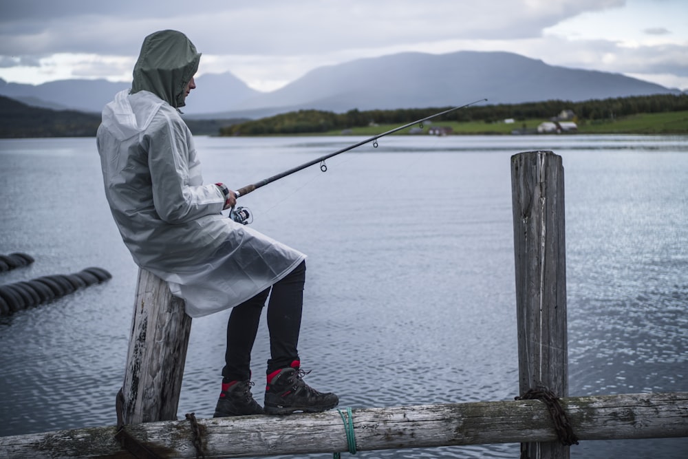 man in white jacket fishing on sea during daytime