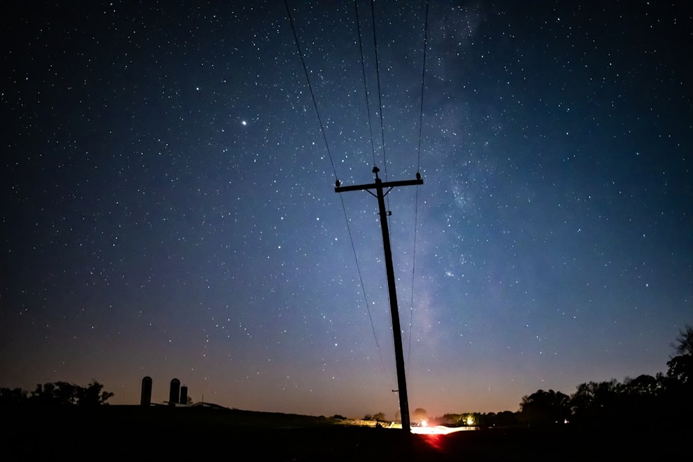 silhouette of person standing on top of post during night time