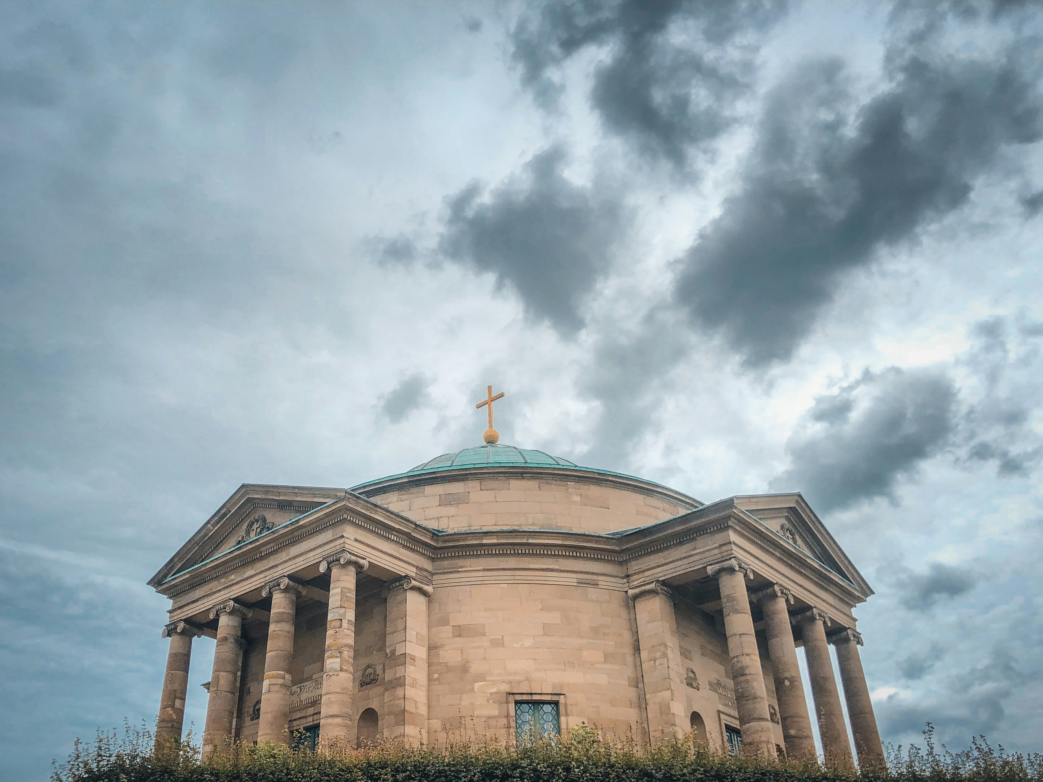 Bâtiment en béton brun sous un ciel nuageux pendant la journée