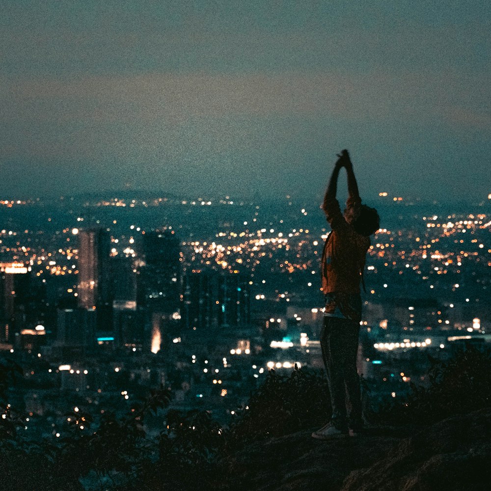 woman in orange tank top standing on rock formation during night time