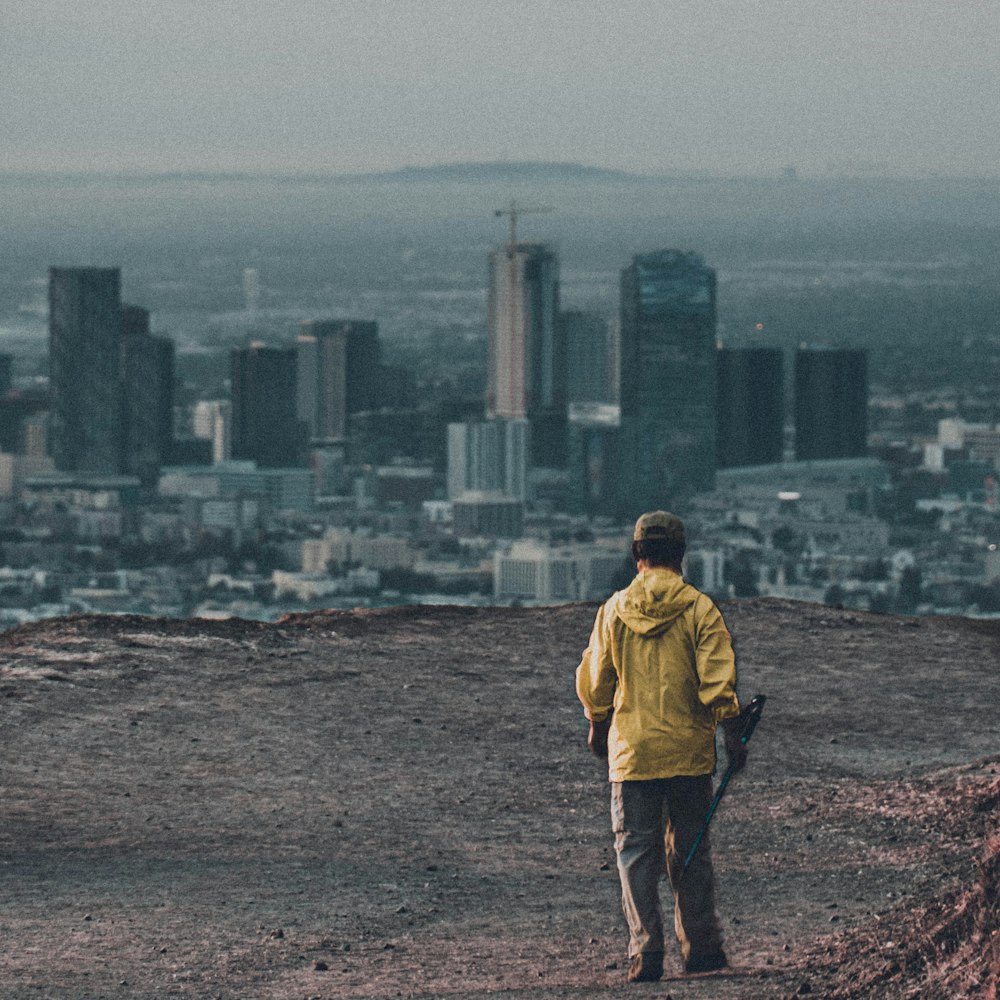 man in yellow jacket standing on brown field during daytime