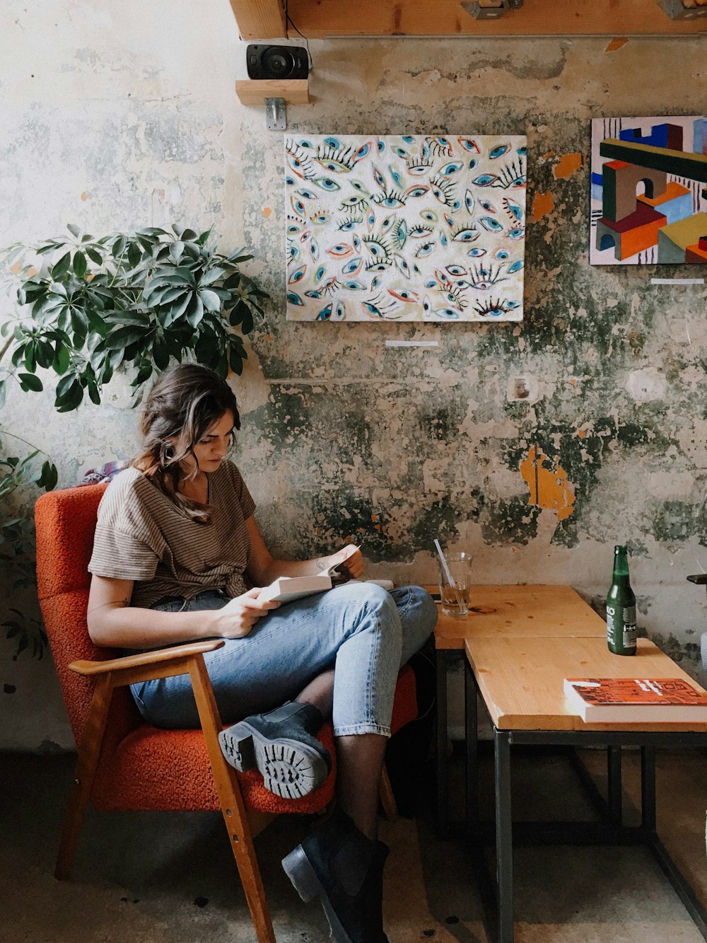 woman in brown long sleeve shirt and blue denim jeans sitting on brown wooden chair