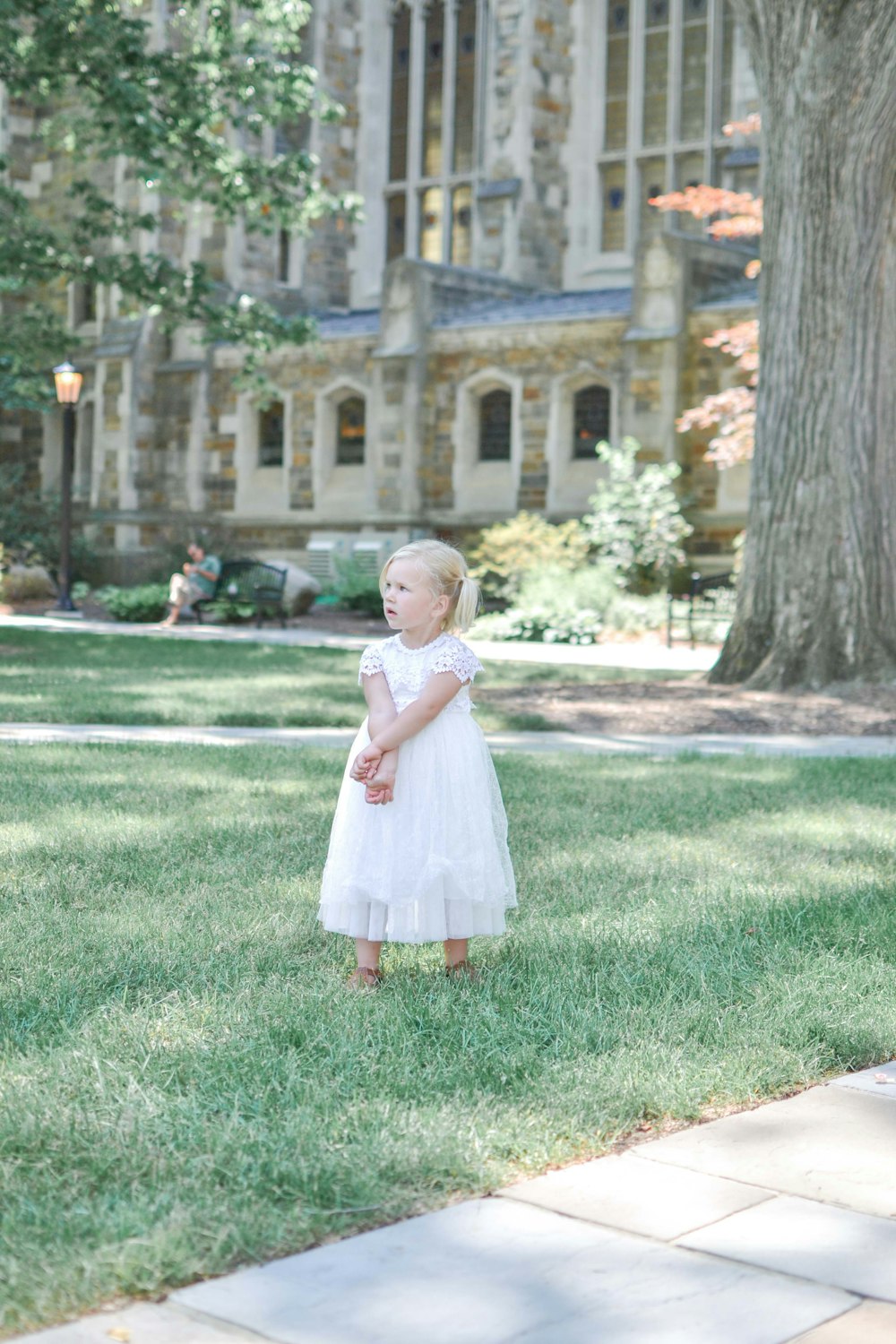 girl in white dress standing on green grass field during daytime