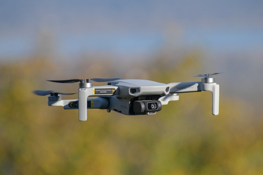 white and gray drone in mid air during daytime