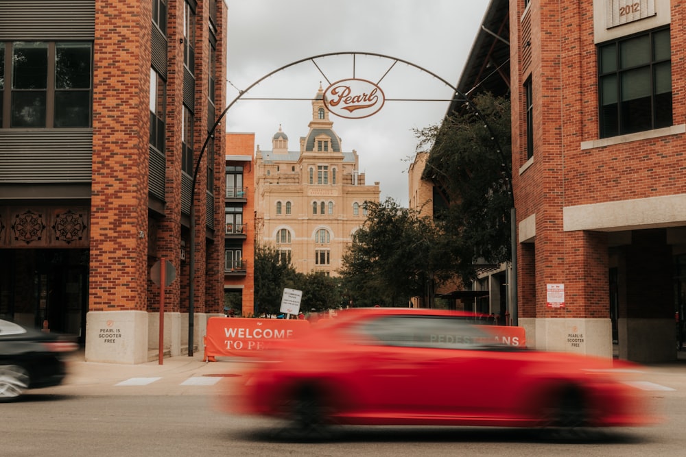 red car on road near brown building during daytime