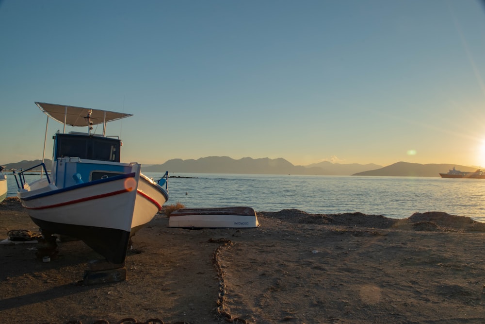 white and blue boat on shore during daytime