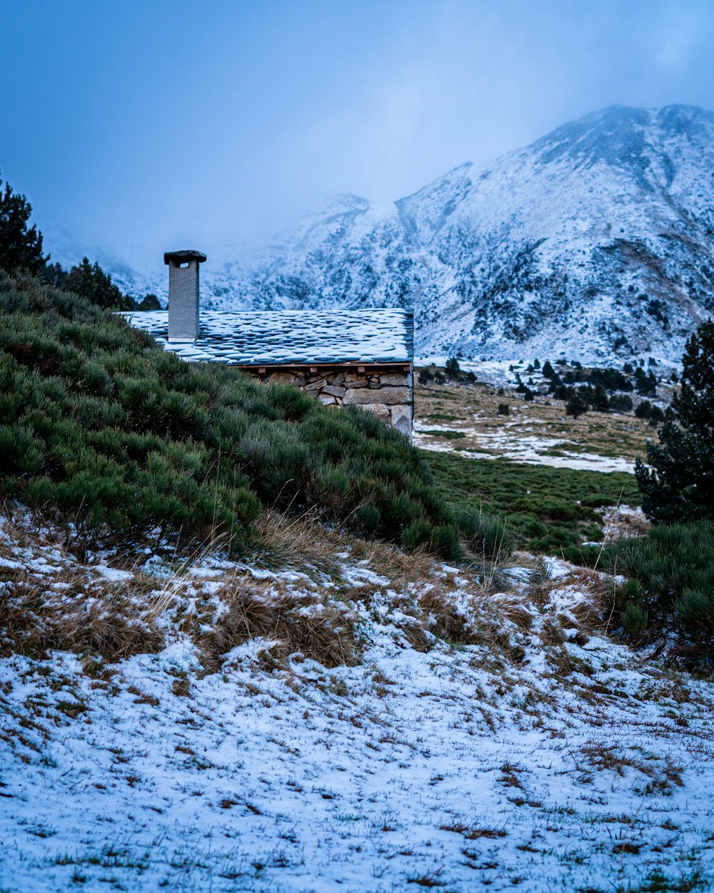 maison blanche et brune près de la montagne sous le ciel bleu pendant la journée