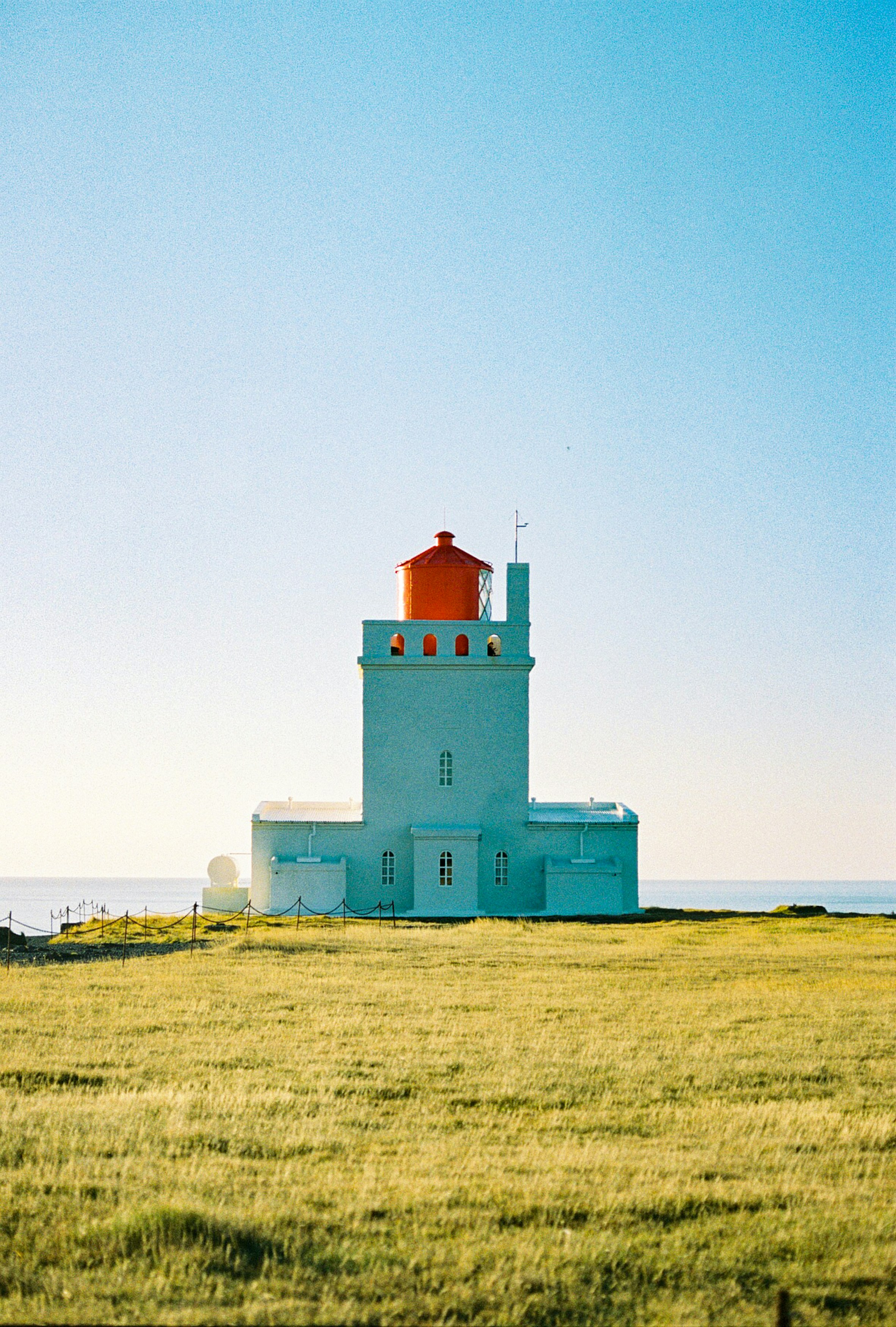 white and red concrete building on green grass field under white sky during daytime
