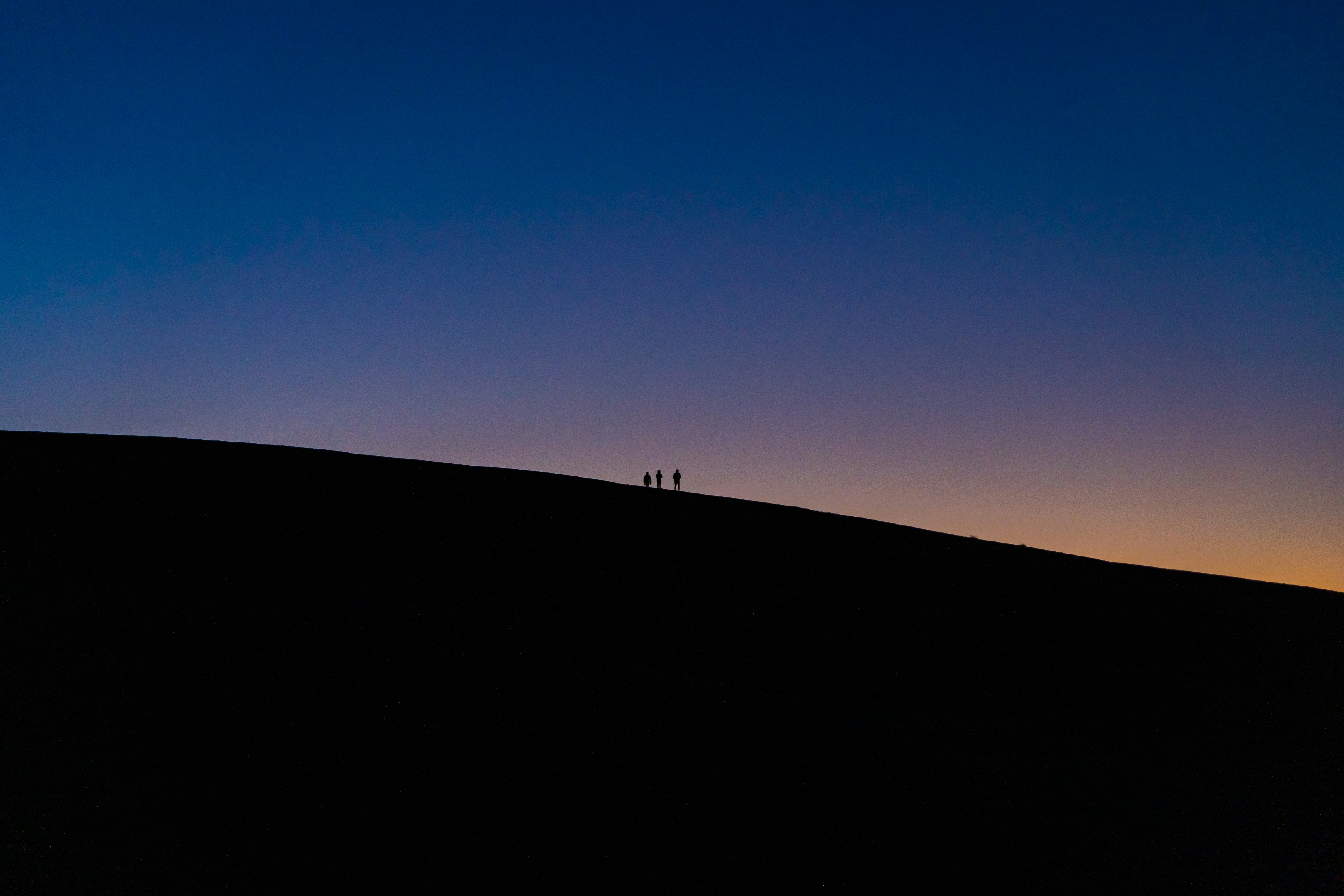 Silhouette von Menschen, die nachts auf der Straße spazieren gehen