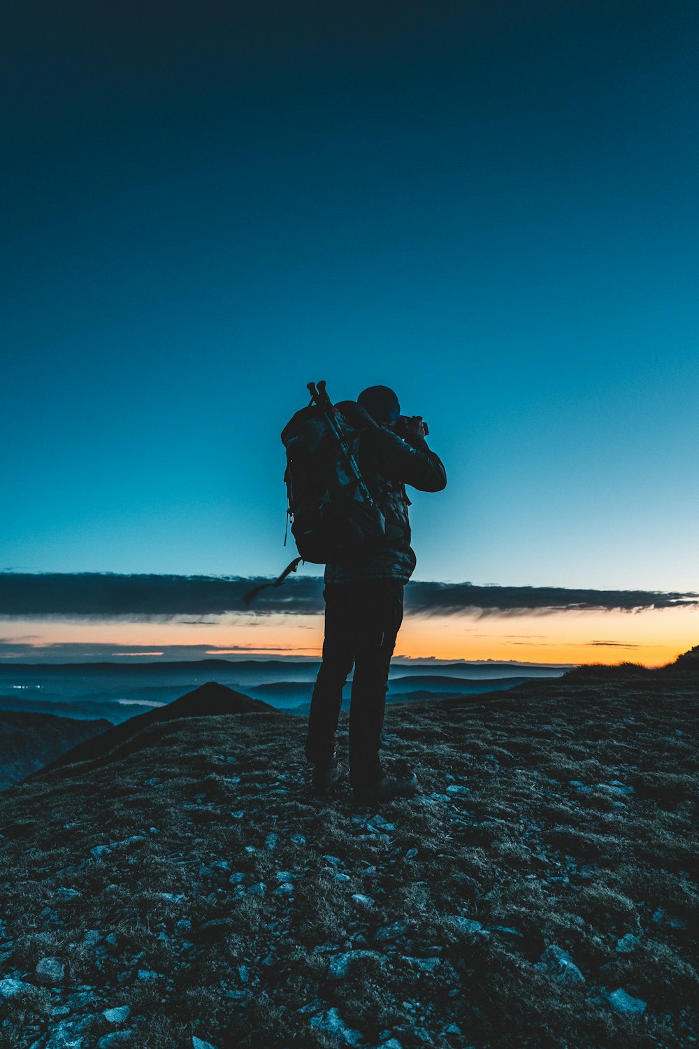 Silueta del hombre de pie sobre la formación rocosa durante la puesta de sol