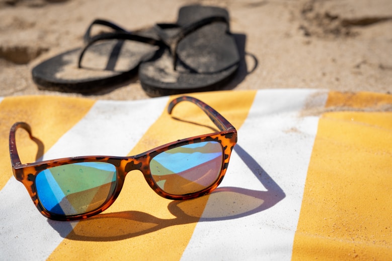 black framed sunglasses on white and brown textile