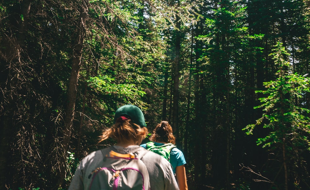 woman in gray shirt standing in the middle of forest during daytime