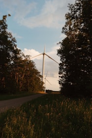 Technicians installing a sleek wind turbine in a green field at sunrise.