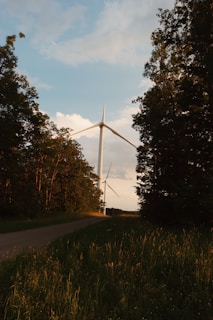 Technicians installing a sleek wind turbine in a green field at sunrise.