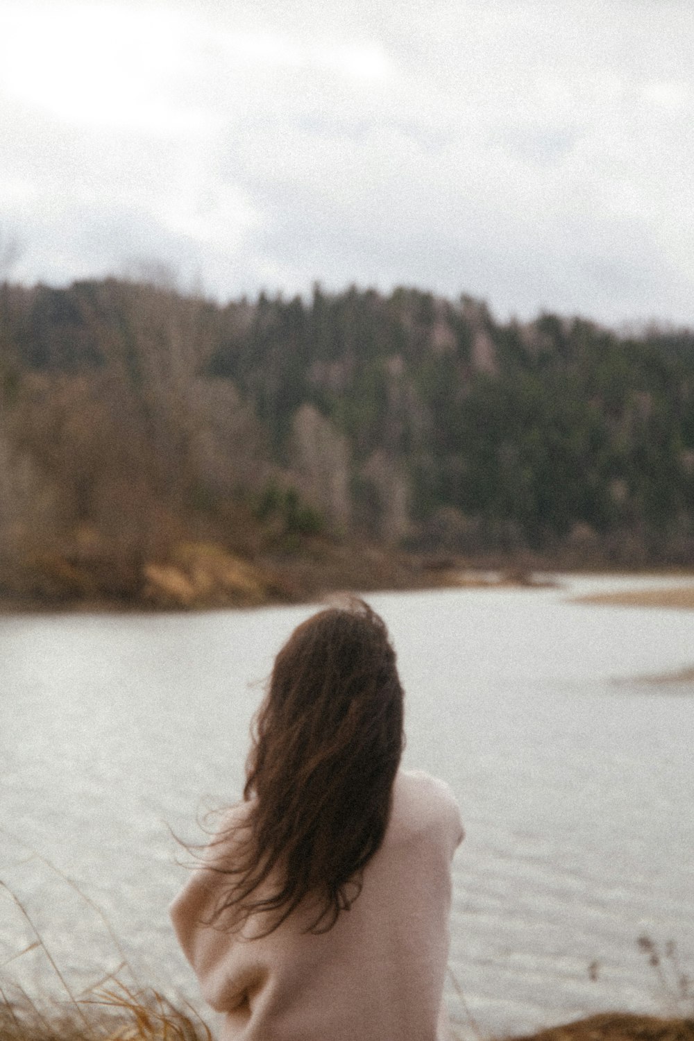 woman in white shirt sitting on white textile near body of water during daytime