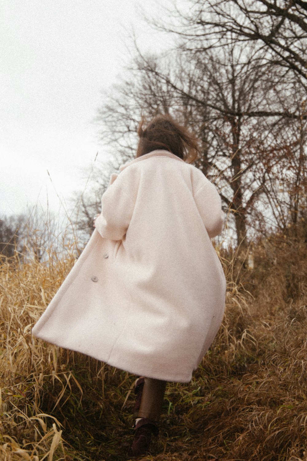 woman in white long sleeve shirt standing on brown grass field during daytime