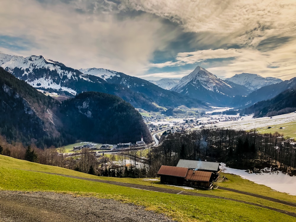 brown wooden bench on green grass field near snow covered mountains during daytime