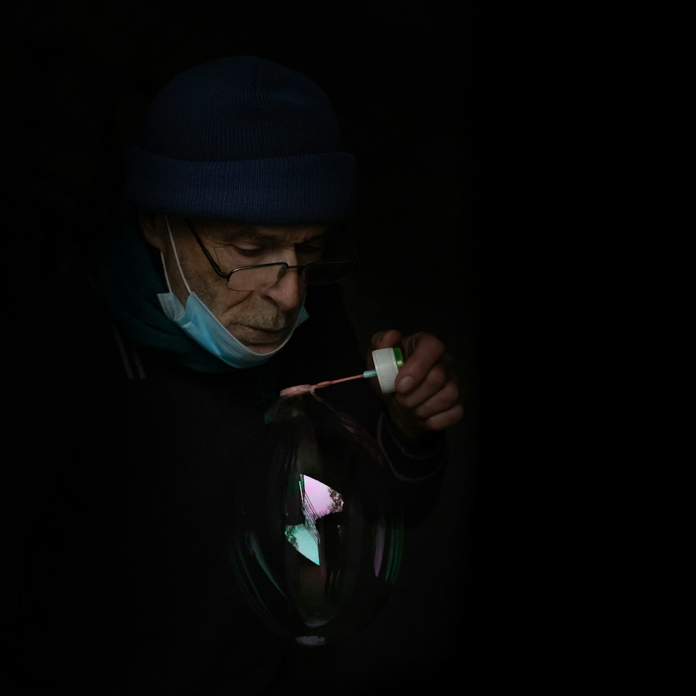 Hombre con gorra de punto azul y sudadera con capucha negra fumando cigarrillos