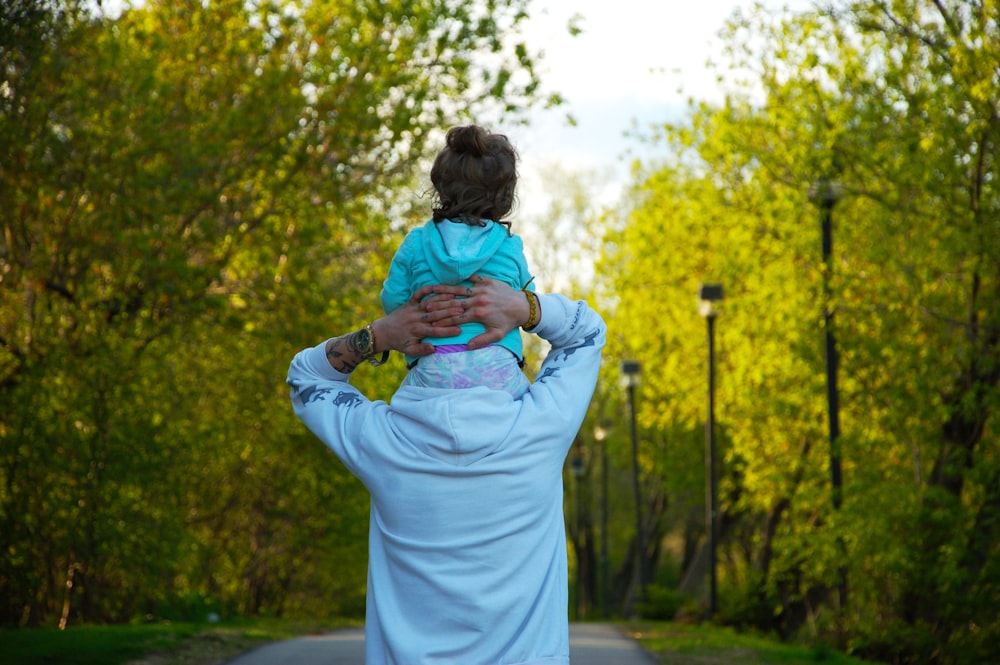 woman in white dress carrying baby in blue jacket