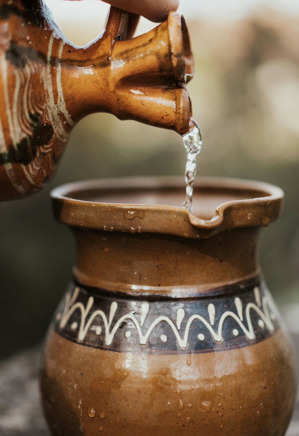 water pouring from brown ceramic vase
