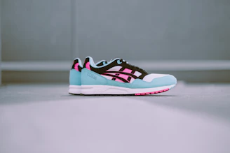 A soft aesthetic styled flat lay of trendy branded sneakers with pastel pink and cream accents.