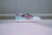 A pair of stylish athletic sneakers is placed on a flat surface. The sneakers feature a striking color combination of pastel blue, black, white, and vibrant pink. The design includes a sleek logo on the side and a textured sole.