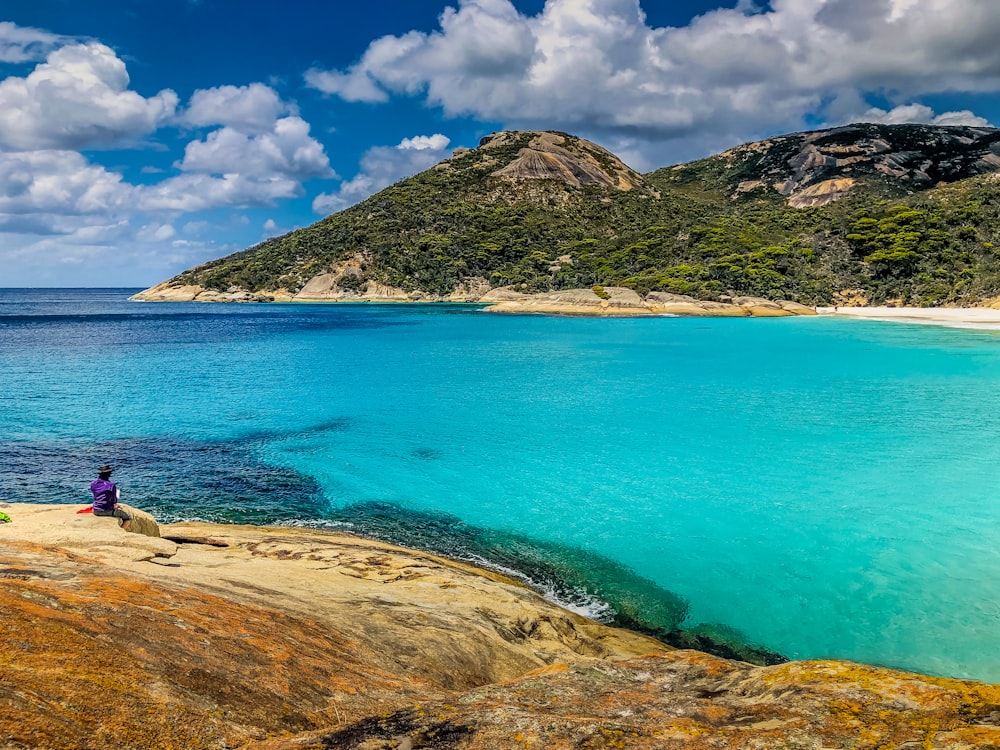 blue sea beside brown mountain under blue sky during daytime