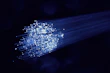 Image of fiber optic cables glowing with blue light against a dark background
