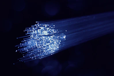 Fiber optic cables glowing with light, coiled neatly on a dark surface.