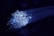 A cluster of glowing fiber optic cables emitting bright blue light against a dark background. The cables appear to be bundled together, with individual fibers visible, creating a starry effect as they disperse light.