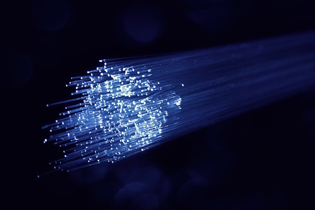 Close-up of glowing optical fiber cables illuminating in a dark room.