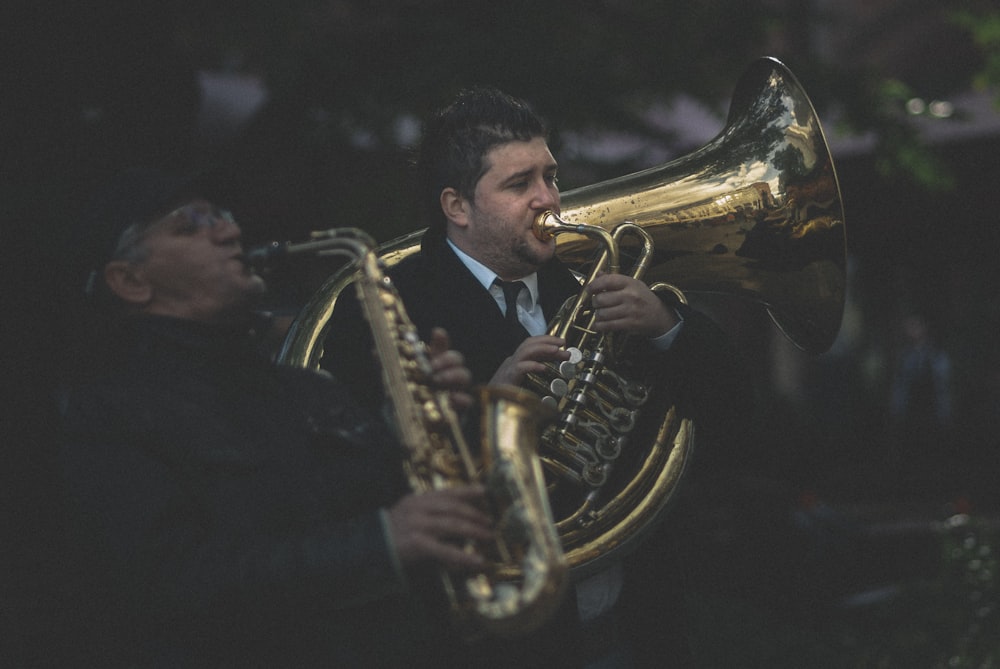 man in black suit playing brass saxophone