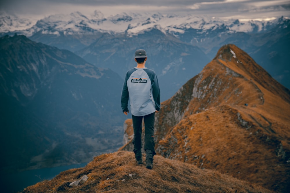 man in white jacket standing on brown rock mountain during daytime