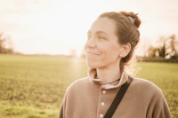 woman in brown long sleeve shirt standing on green grass field during daytime