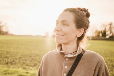 woman in brown long sleeve shirt standing on green grass field during daytime